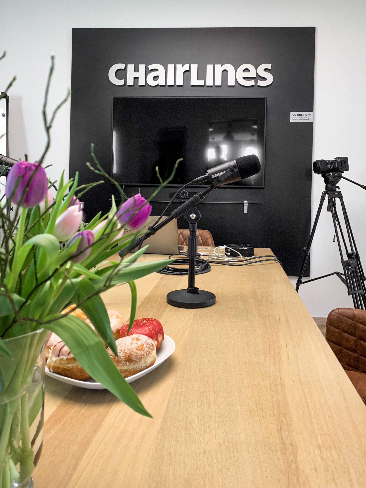 Podcast-Studio der Chairlines mit Mikrofon, Tulpen und Kamera auf Stativ