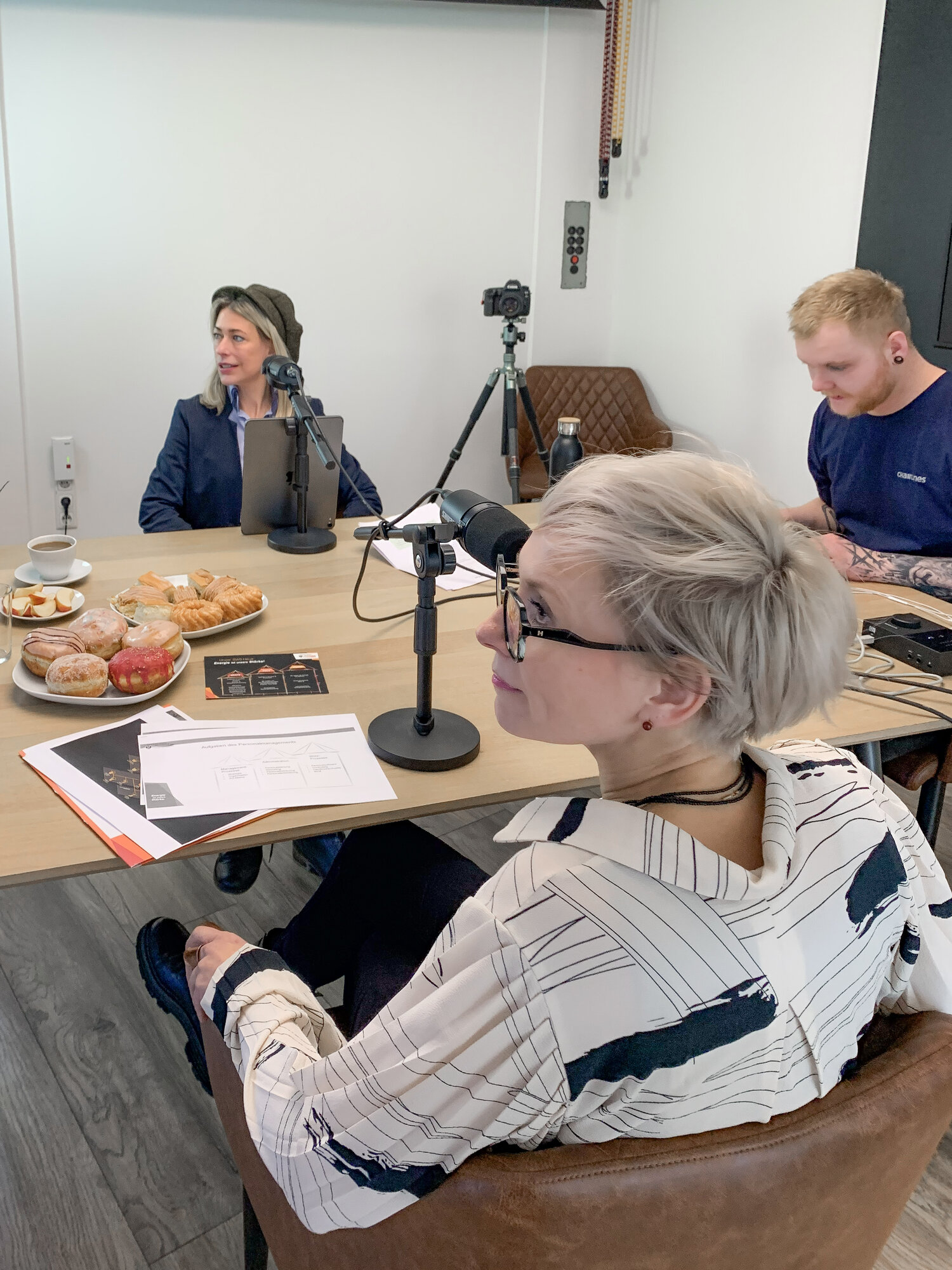 Drei Personen bei einer Podcast-Aufnahme am Tisch