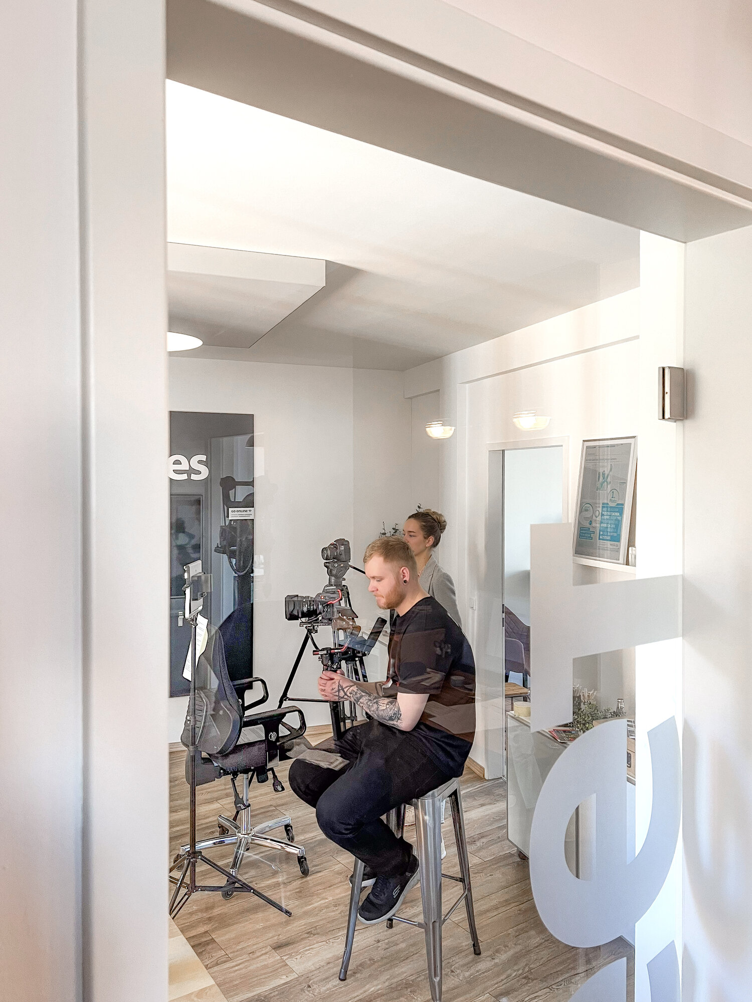 Kameramann beim Filmen durch die Glastür in das Podcast-Studio