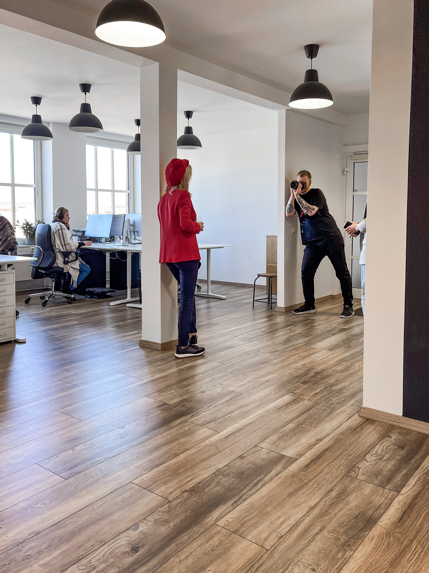 otoshooting im Büro: Kameramann fotografiert Frau in rotem Outfit