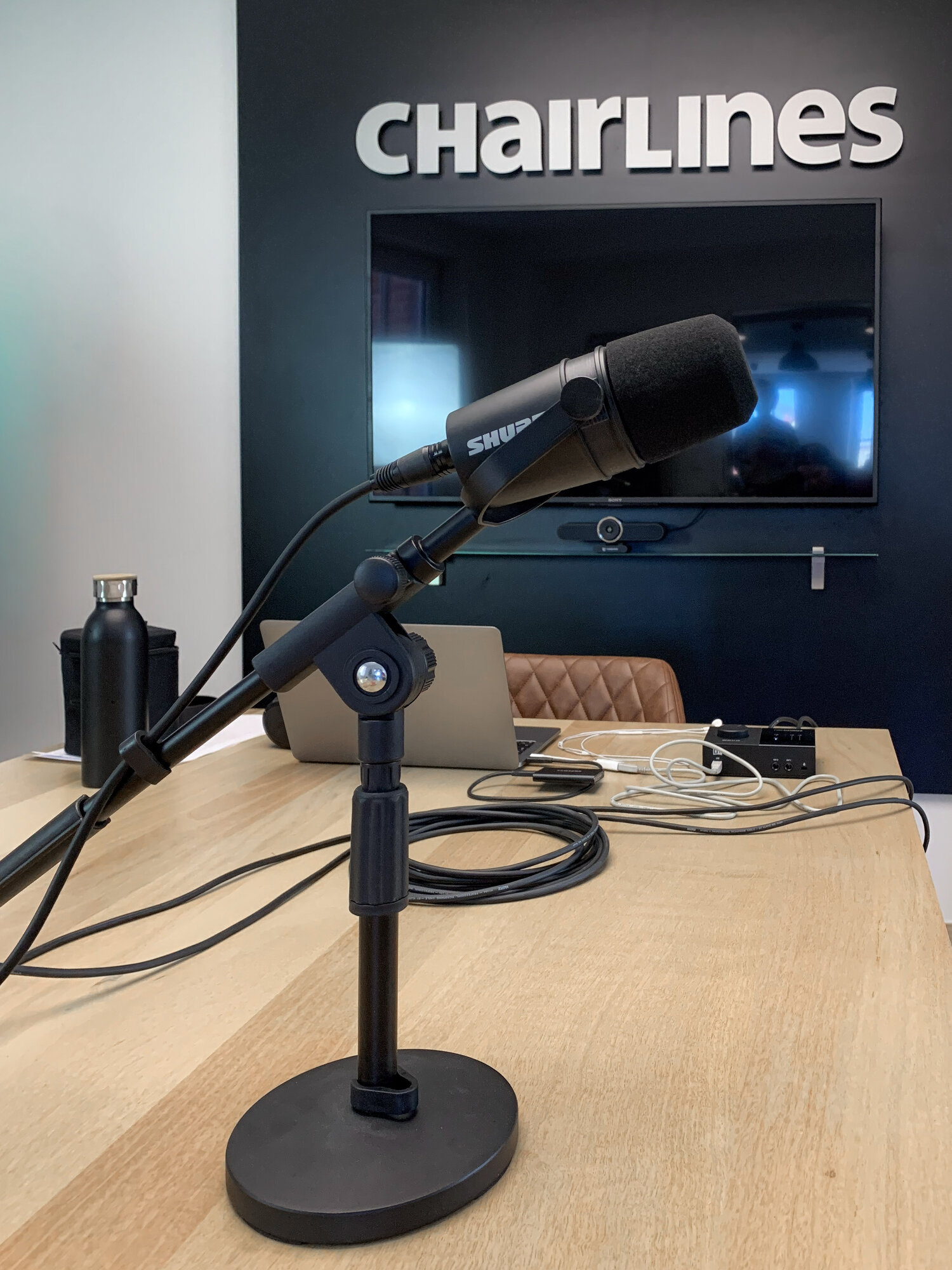 Nahaufnahme eines Shure-Mikrofons auf Tischstativ im Chairlines Podcast-Studio
